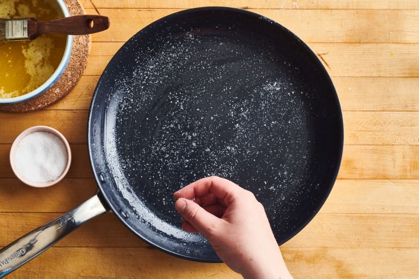 someone is putting salt on a pan