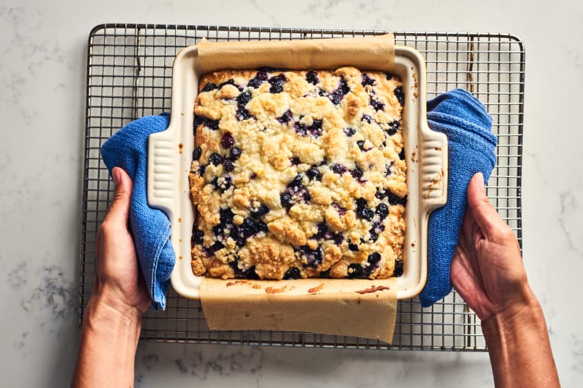 someone putting blueberry buckle on cooling rack