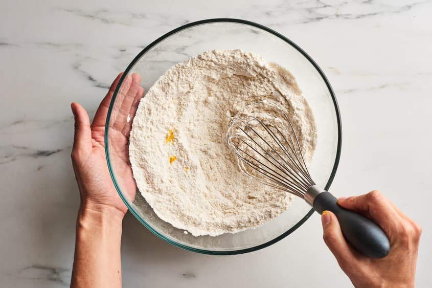 someone is mixing together flour and ingredients with whisk