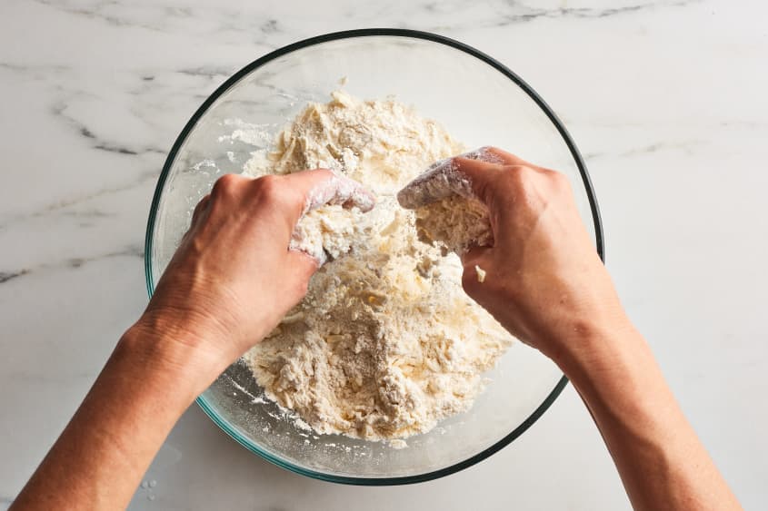 someone is mixing together flour and ingredients with hands