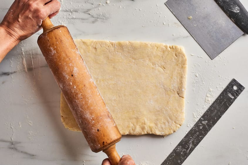 someone is using a rolling pin on scone dough