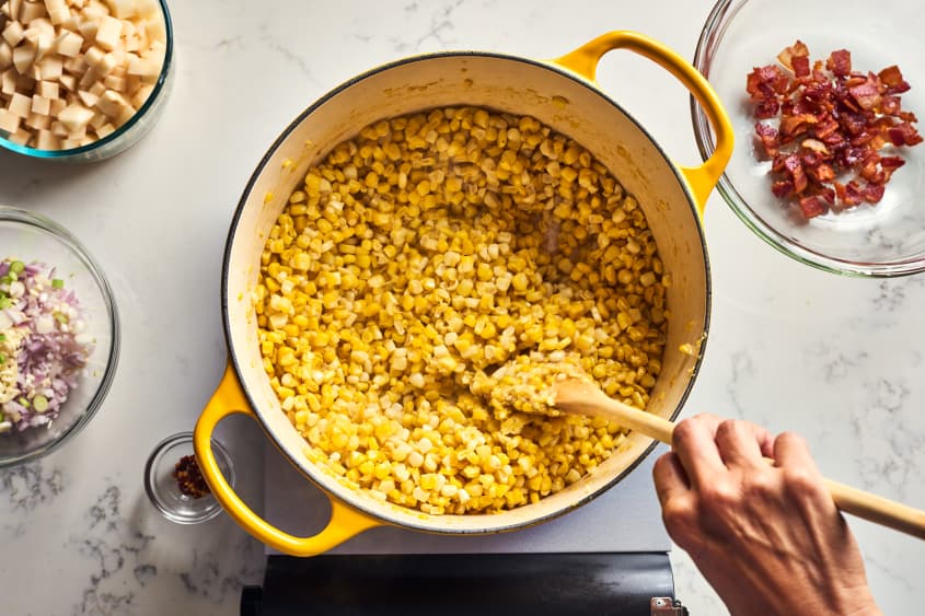 someone mixing corn in pot
