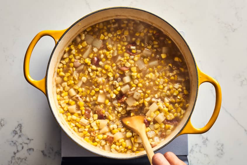 someone mixing corn chowder in a pot