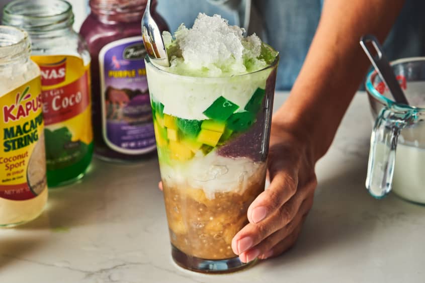 someone stacking ingredients in halo halo, shaved ice on top