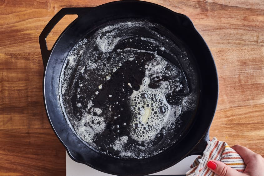 someone melting butter in a cast iron pot