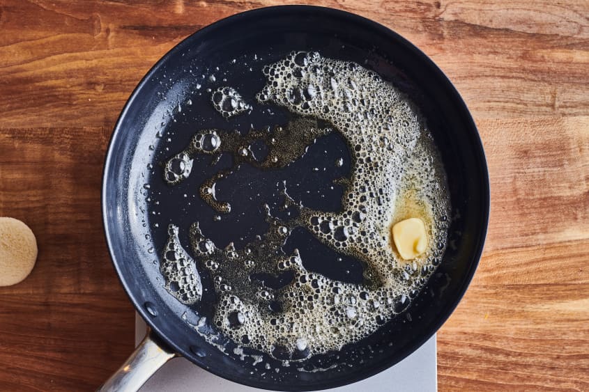 someone melting butter in a cast iron pan