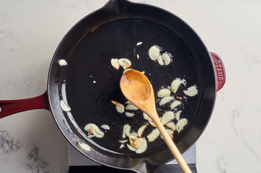 someone sauteeing garlic in cast iron pan