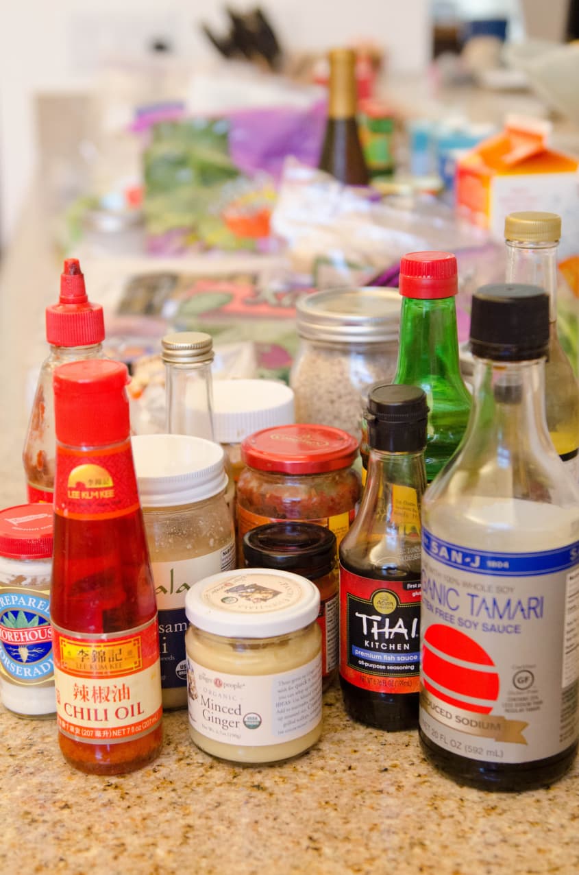 Assorted Asian condiments and sauces on a kitchen counter, including chili oil, minced ginger, and soy sauce.