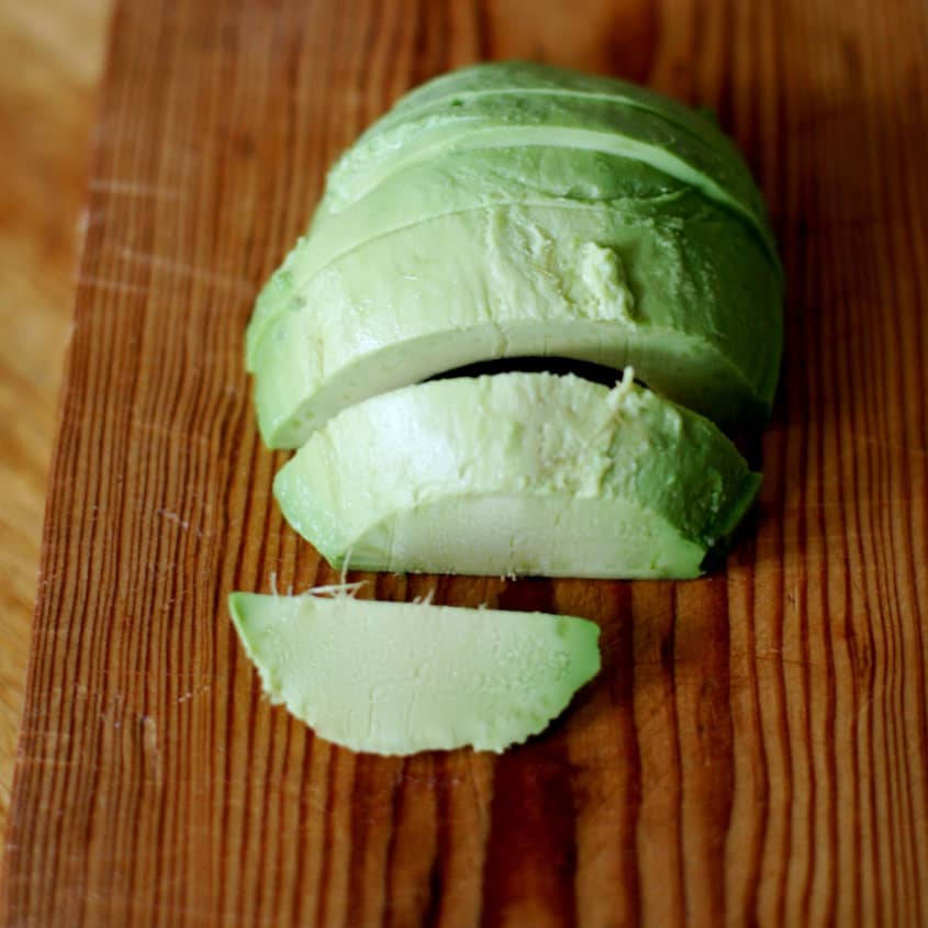 Sliced avocado on a wooden cutting board.