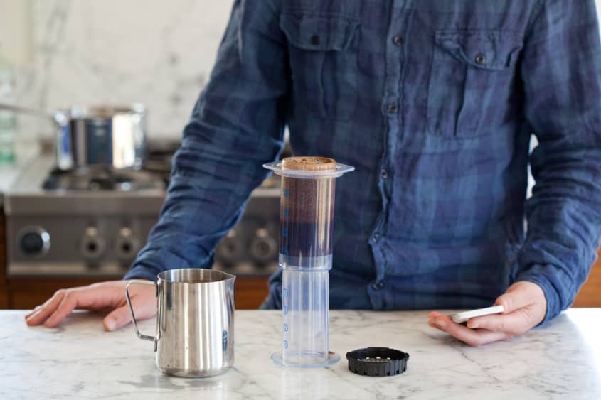 Free Photo  Step by step aero press coffee preparation barista in blue  jeans shirt pours hot boiled water from teapot to aeropress professional  coffee brewing cafe shop