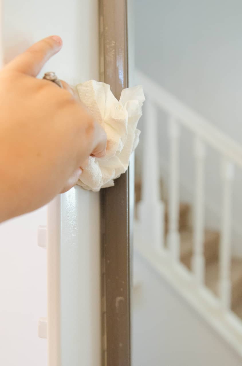 Hand cleaning a refrigerator door seal with a paper towel.