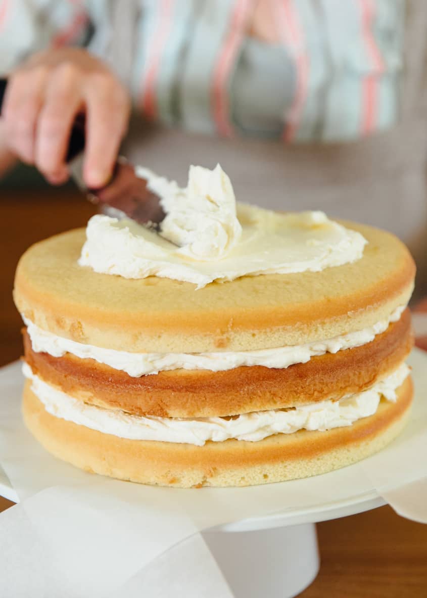 Three-layer white cake, top layer being frosted with white frosting