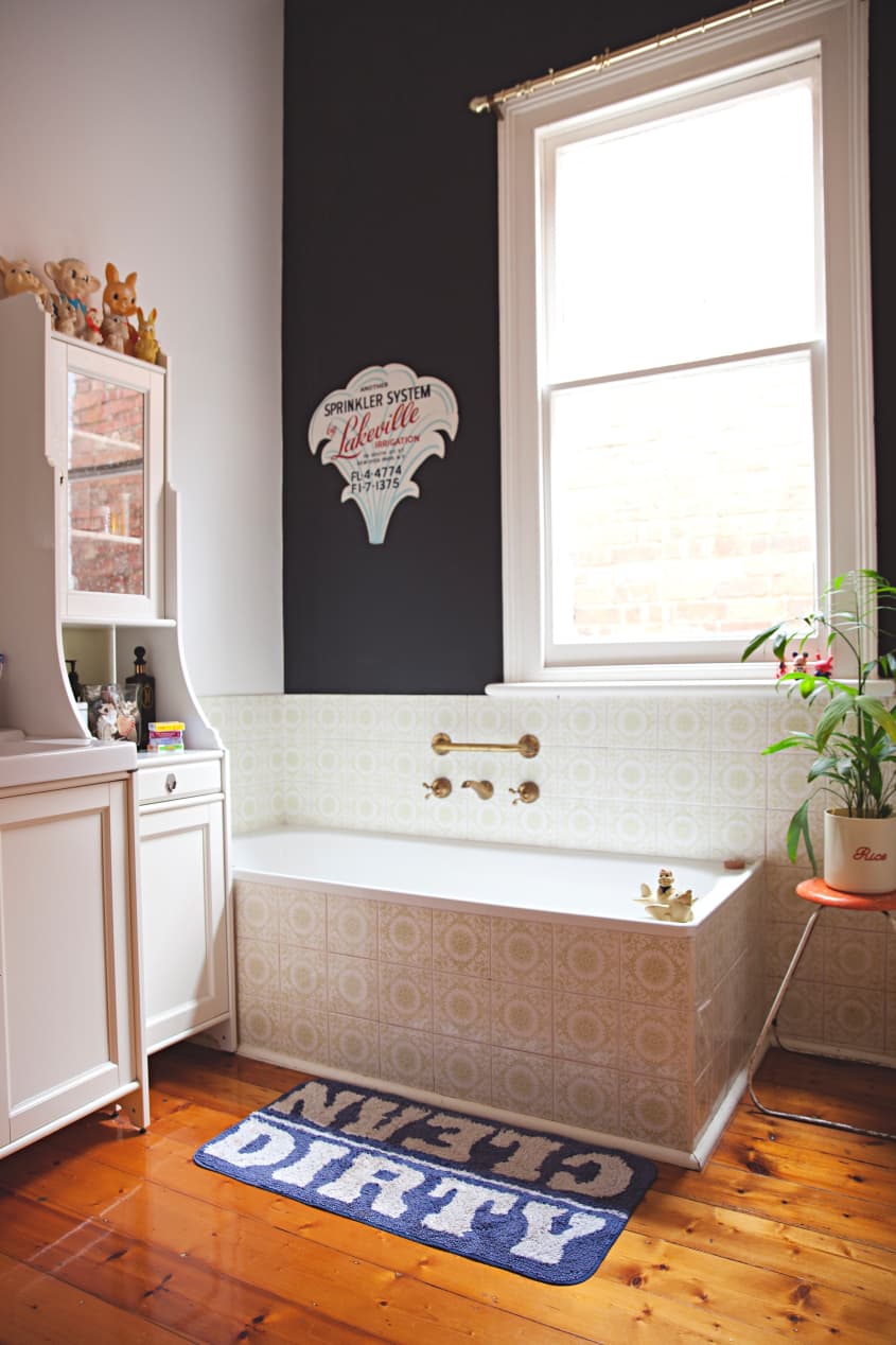 A bathroom with a large tiled tub and a black accent wall