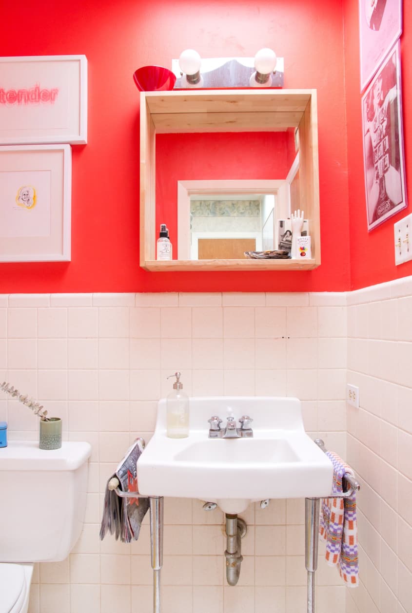 neon paint and white tile bathroom has a light fixture with two exposed bulbs above the sink