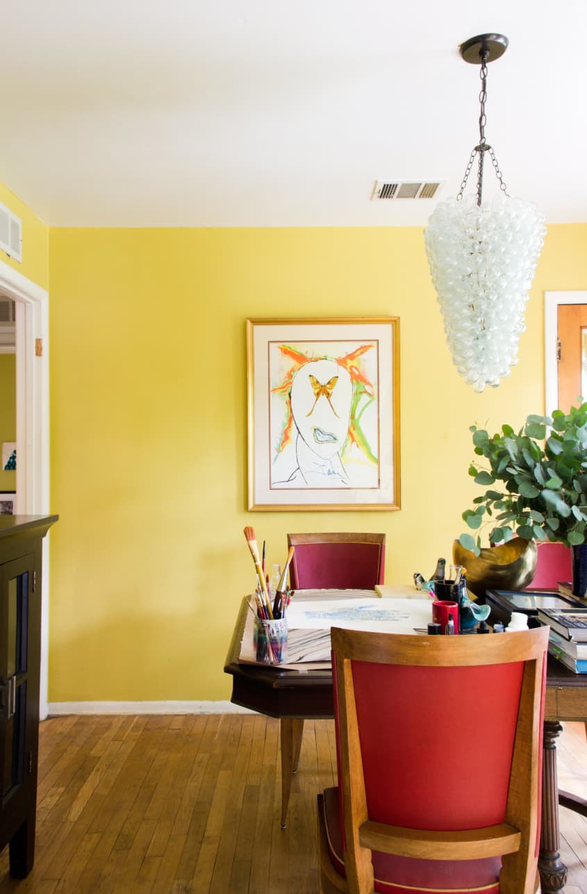 a yellow dining room with red chairs at the table