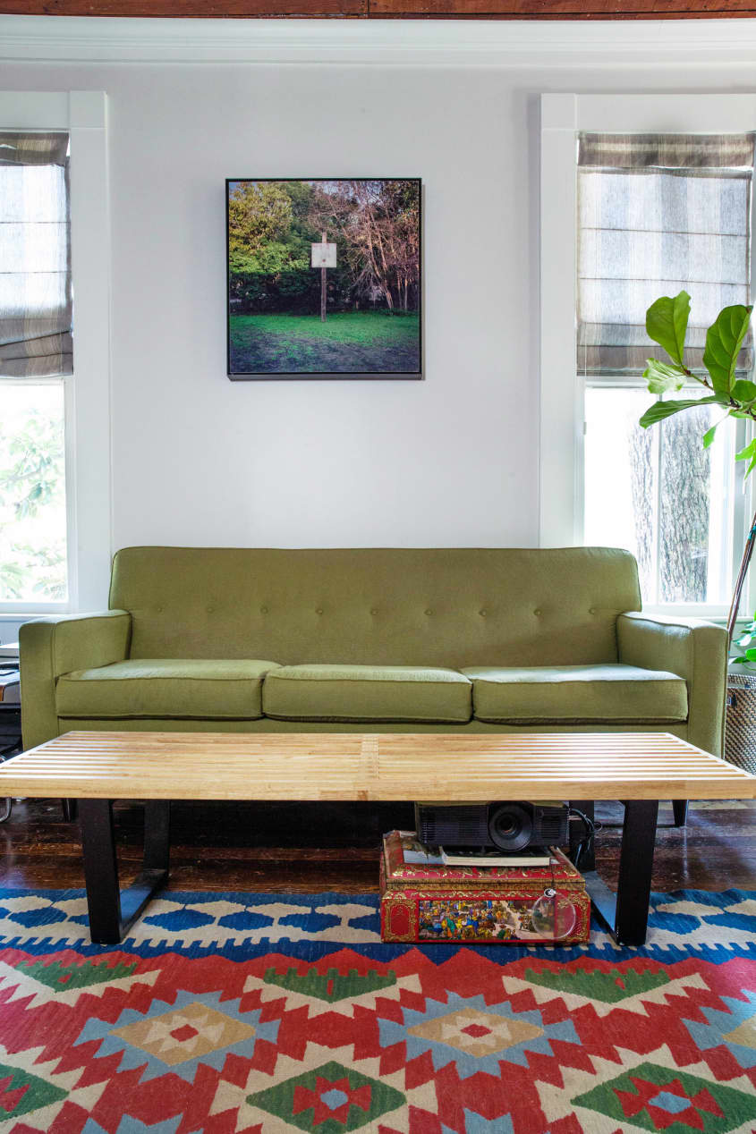 a living room with a mid-century modern green couch and an abstract rug