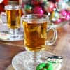 Glass mug of Rye and Ginger Hot Toddy on a saucer with festive cookies.