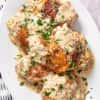 Platter filled with chicken thighs in a creamy French mustard sauce cooking in a slow cooker