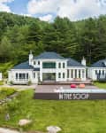 Large white house with blue roof, surrounded by trees, features a pool and deck with colorful bean bags, labeled "In the Soop."