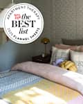 Cozy bedroom with warm bedding and striped sheets with Best List seal in upper left