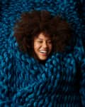 Person smiling, wrapped in a thick, chunky blue knit blanket.