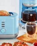 Blue kitchen appliances set with kettle, toaster, coffee maker, and egg cooker on a countertop.
