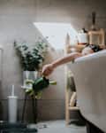 A little girl holds a bath toy outside a roll top bath