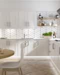 Modern kitchen with white cabinets, chevron backsplash, wooden shelves, and a round dining table with white chairs.