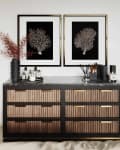 Wooden dresser with black marble top, decorative vases, candles, and framed coral prints on the wall.
