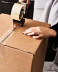 A tape roller goes across the bottom of a cardboard box to prepare for a move