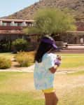 Two girls walking on a grassy area near a building with desert hills in the background.