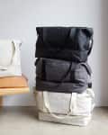 Tan leather bench with pillows, stacked travel bags, and brown ankle boots on concrete floor.