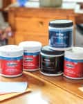 various paint sample pots sitting on a table with some paper paint swatches