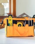 bright yellow-orange tool bag with tools inside. Sitting on counter in home setting