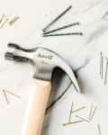 a hammer and different kinds of nails on a marble surface