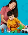 Woman and child playing with colorful recycling-themed toy blocks and truck.