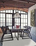 Industrial-style dining room with glass table, black chairs, geometric rug, and large windows.