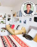 Cozy living room with yellow sofa, colorful pillows, wall art, and a cat on a patterned bedspread.