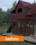 Wooden playhouse with slide and ladder in a backyard, RV in background.