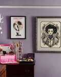 Purple room with framed art, jewelry box, and wall-mounted antlers displaying necklaces.