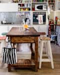 A white kitchen with a wood island, open shelving, and rustic/cottagecore elements to the space