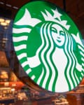 Starbucks logo on a glass window with a view of the store interior and street outside.