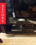 Dark wood TV stand with a flat-screen TV, DVD player, and gaming console, on a woven rug.