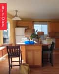 Kitchen with wooden cabinets, white appliances, and a central island with boxes and a plant.