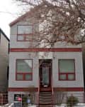 Two-story gray house with red trim, front steps, and bare tree branches.