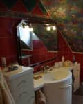 Bathroom with red tiles, floral ceiling, white sink, and mirror under angled window.