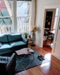 Living room with a blue sofa, black armchair, typewriter, globe, and a view into a study with a desk and chair.