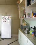 Vintage kitchen with mint green cabinets, white fridge with magnets, stainless steel sink, and open shelves with various items.