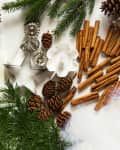 Pinecones, cinnamon sticks, evergreen branches, and metal molds arranged for holiday crafts.