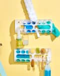 Cleaning supplies organized on wall racks, with a turquoise ironing board and a light blue ladder against a yellow wall.